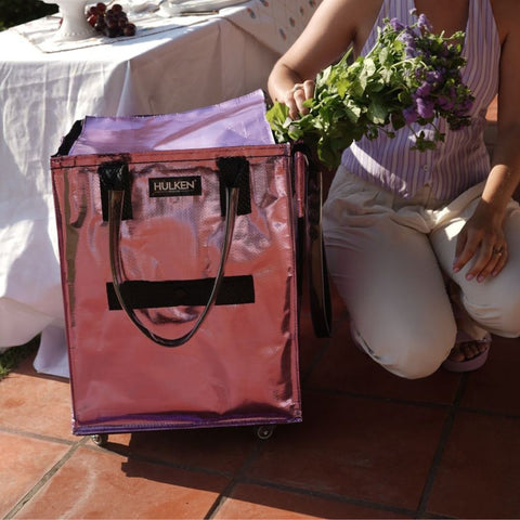 Person holding a bouquet of flowers next to a lilac tote